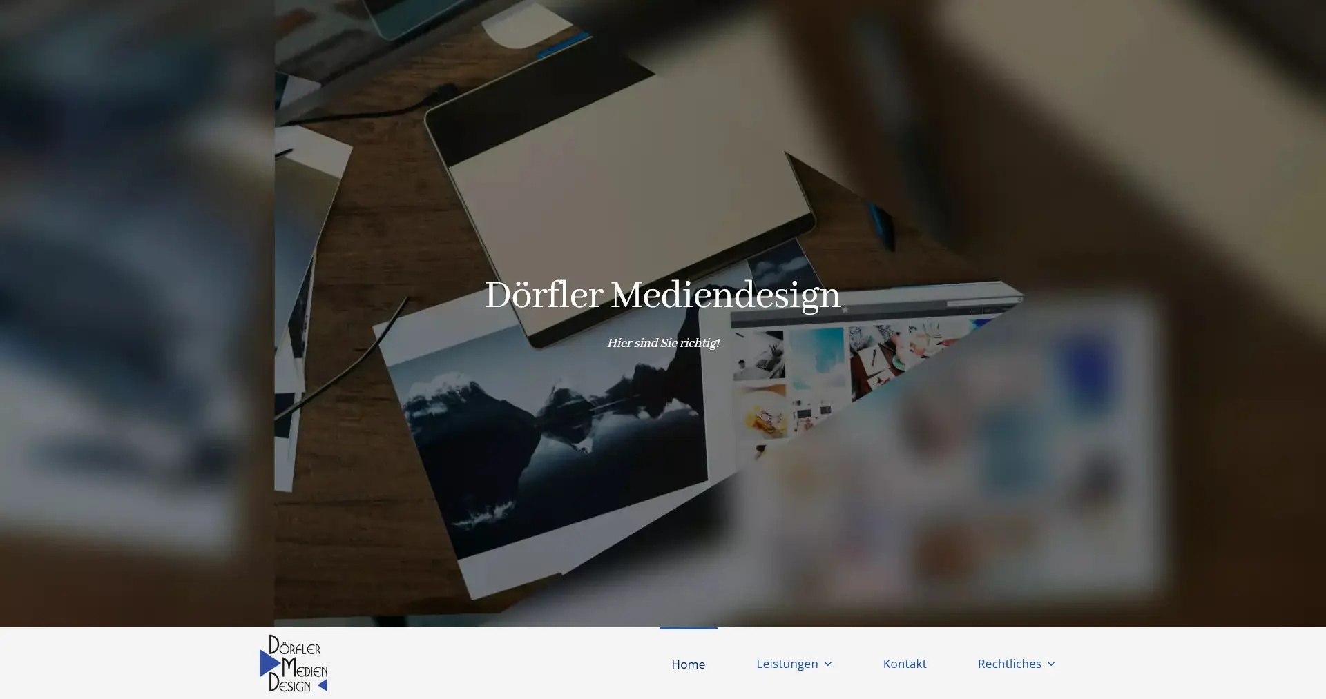 Arbeitsbereich von Dörfler Mediendesign mit verschiedenen Druckmaterialien und einem Computer.